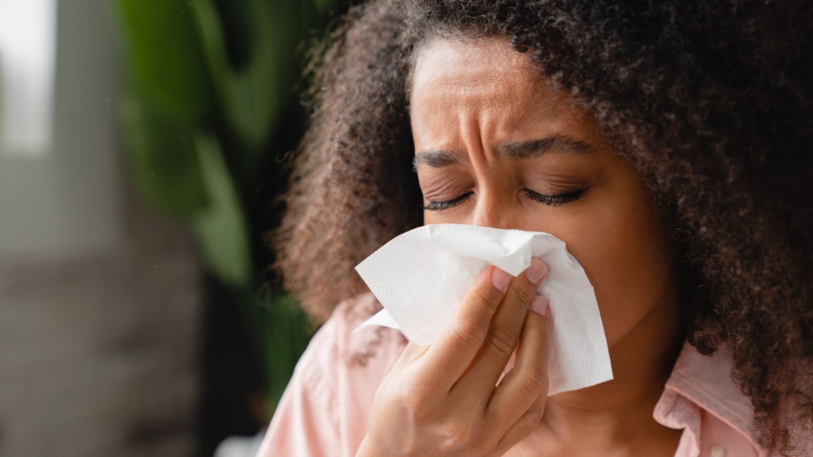 African American woman sneezing into a tissue