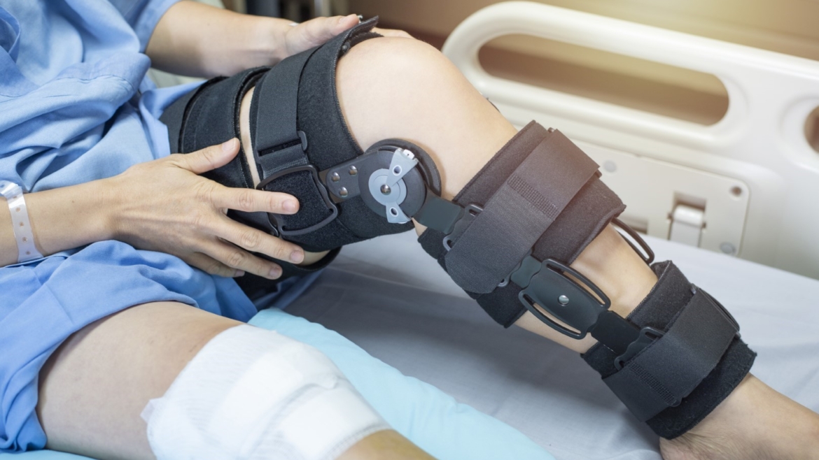 Woman in hospital bed with knee brace on recovering from knee surgery