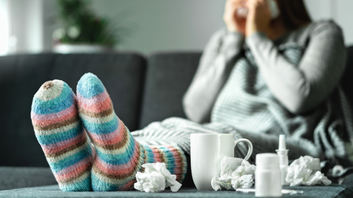 Woman on couch sick with the flu blowing her nose