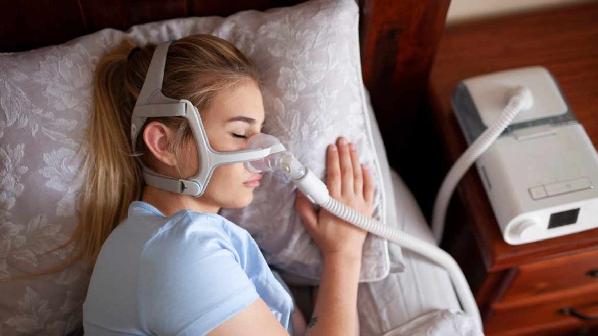 Young female sleeping with CPAP machine for sleep apnea.